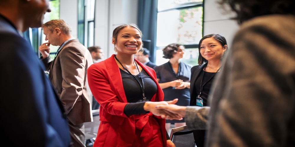 Confident businesswomen handshaking while standing in corridor of an auditorium. Female professionals greeting each other convention center.