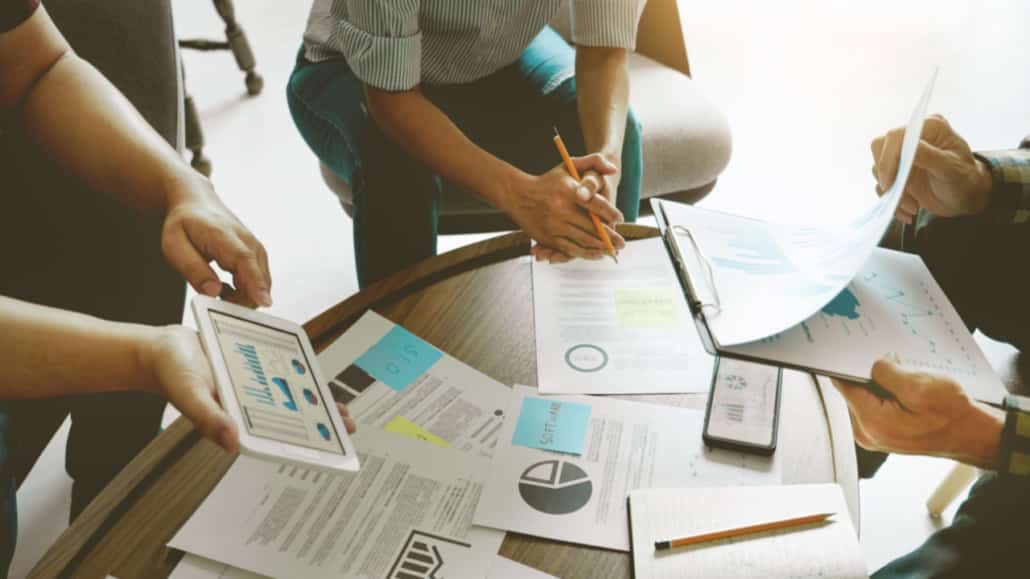 Group-of-people-around-a-low-table-with-business-documents-laid-out-1030x579